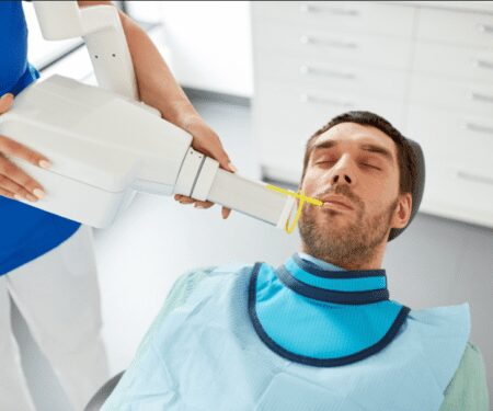 This image shows a photo of a man receiving an X-ray at a dental clinic